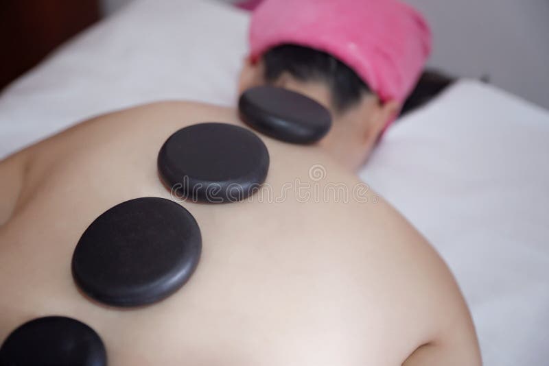 Femme adulte ayant le massage en pierre chaud dans le salon de station thermale image stock Femme adulte ayant le massage en pierre chaud dans le salon de station thermale image stock