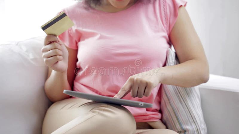 Femme africaine heureuse avec le PC de comprimé et la carte de crédit
