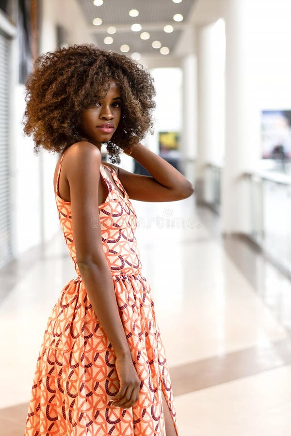 Femme africaine heureuse dans la belle robe dans un centre commercial photo stock Femme africaine heureuse dans la belle robe dans un centre commercial photo stock
