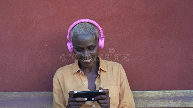 Femme africaine heureuse à l'aide du mobile smartphone tandis que l'écoute de la musique avec des écouteurs clips vidéos