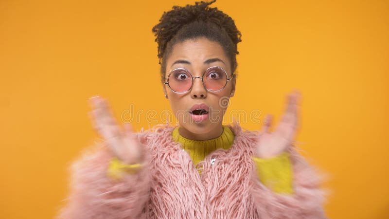 Femme afro-américaine dans le manteau rose drôle étonnée par des nouvelles intéressantes, bavardage