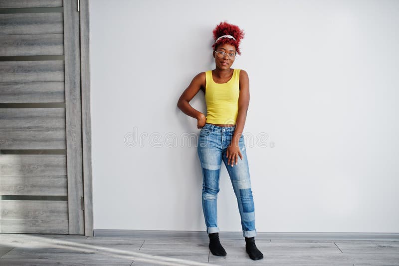 Femme afro-américaine en singlet jaune et lunettes contre mur blanc photographie stock libre de droits