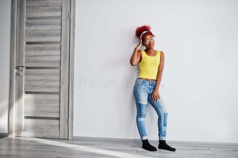 Femme afro-américaine en singlet jaune et lunettes contre mur blanc photos stock