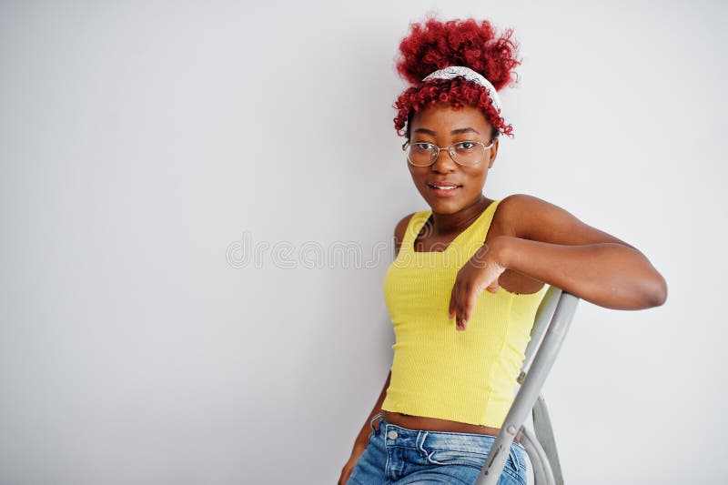 Femme afro-américaine en singlet jaune et lunettes contre mur blanc stand om échelle en fer photos stock