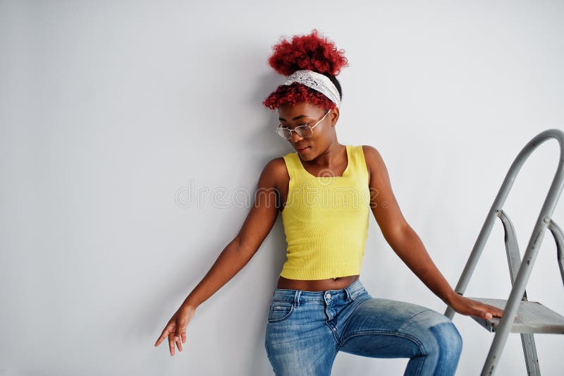 Femme afro-américaine en singlet jaune et lunettes contre mur blanc stand om échelle en fer photos libres de droits