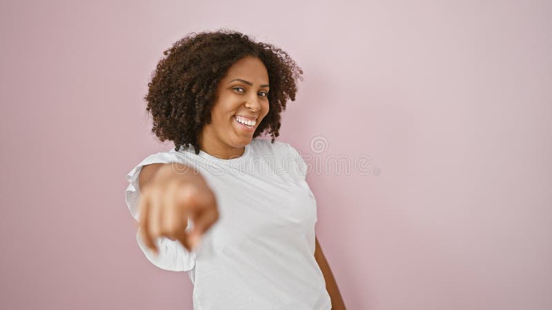 Femme afro-américaine souriante pointée isolée sur fond rose image libre de droits