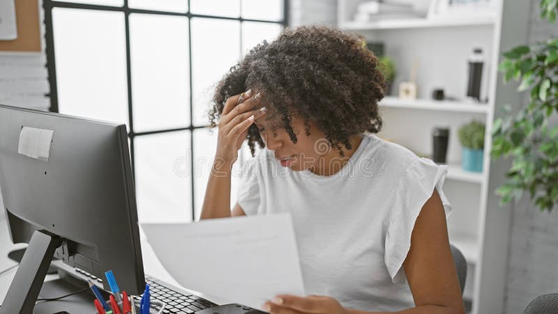 Femme afro-américaine stressée avec des documents dans un bureau images stock