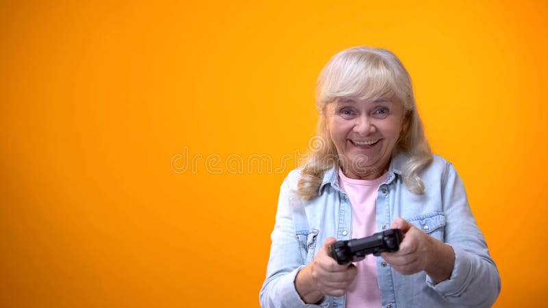 Femme ag?e optimiste active jouant le jeu d'ordinateur, manette de participation, instrument photos stock Femme ag?e optimiste active jouant le jeu d'ordinateur, manette de participation, instrument photos stock