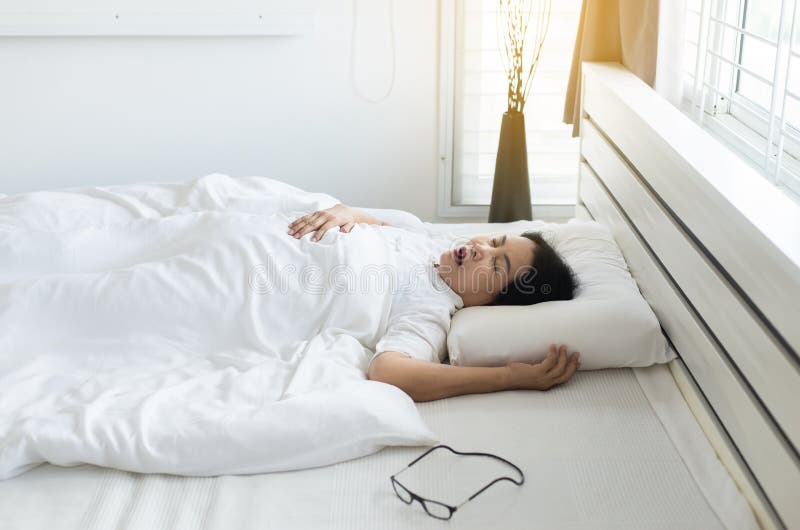 Femme agée asiatique ronflant parce qu'en raison de fatigué du travail, snor femelle tout en dormant sur le lit photographie stock Femme agée asiatique ronflant parce qu'en raison de fatigué du travail, snor femelle tout en dormant sur le lit photographie stock