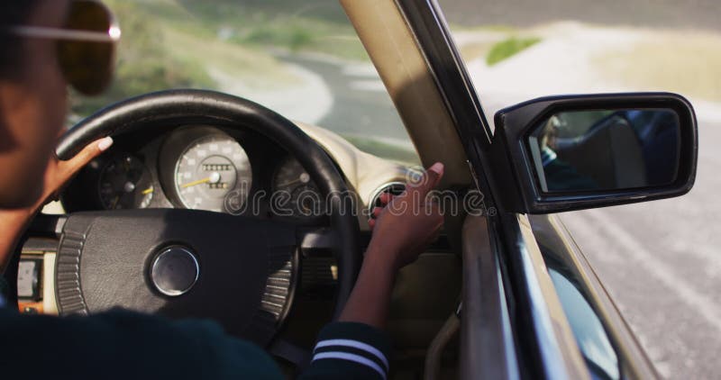 Femme américaine africaine ajustant le rétroviseur de la vue latérale en conduisant dans une voiture décapotable banque de vidéos