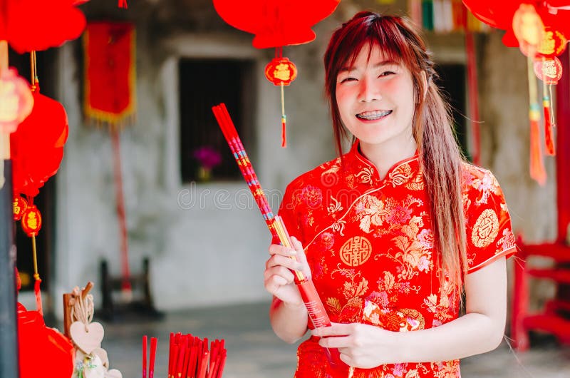 Femme asiatique avec du charme de portrait la belle portent le cheongsam pour s'habiller pour choisir d'acheter l'encens, par nou photo stock Femme asiatique avec du charme de portrait la belle portent le cheongsam pour s'habiller pour choisir d'acheter l'encens, par nou photo stock