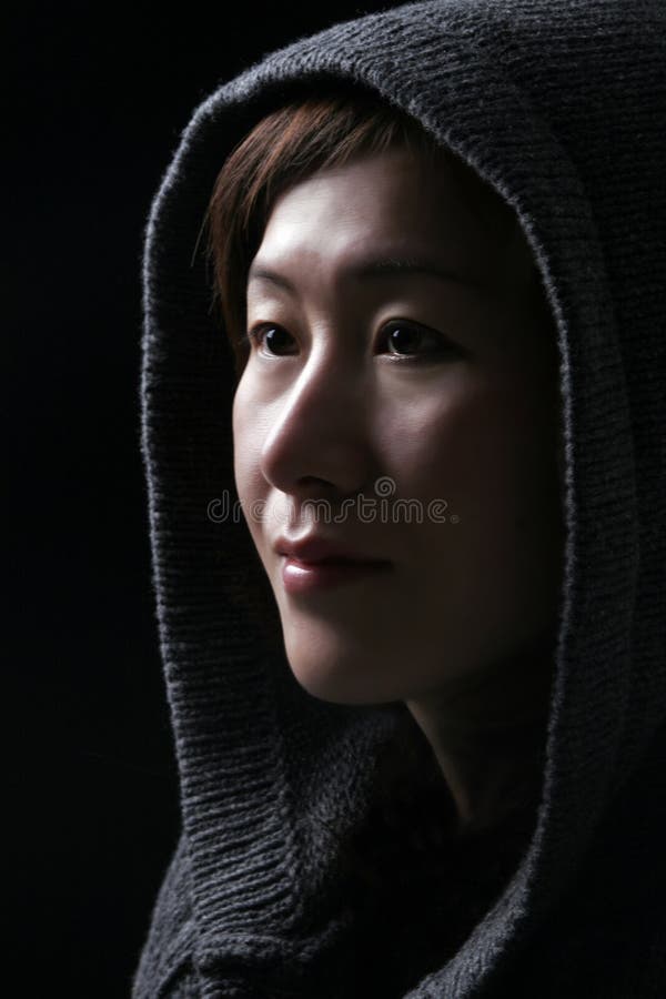 Asian Woman In Deep Thoughts - Hood Over Head - Black Background. Asian Woman In Deep Thoughts - Hood Over Head - Black Background
