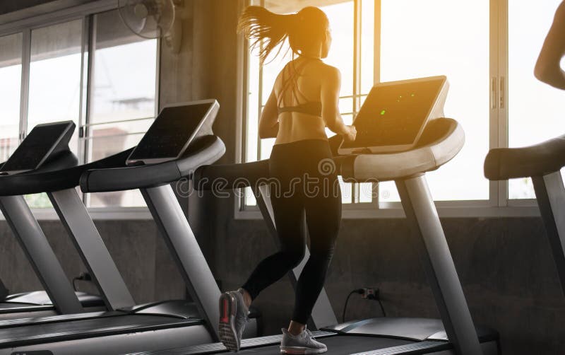 Femme asiatique de sport courant sur des tapis roulants faisant la cardio- formation, corps convenable et musculaire croisés dans photo stock Femme asiatique de sport courant sur des tapis roulants faisant la cardio- formation, corps convenable et musculaire croisés dans photo stock