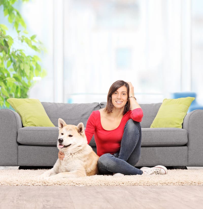 Femme assise sur le plancher à la maison, avec son chien photo stock Femme assise sur le plancher à la maison, avec son chien photo stock