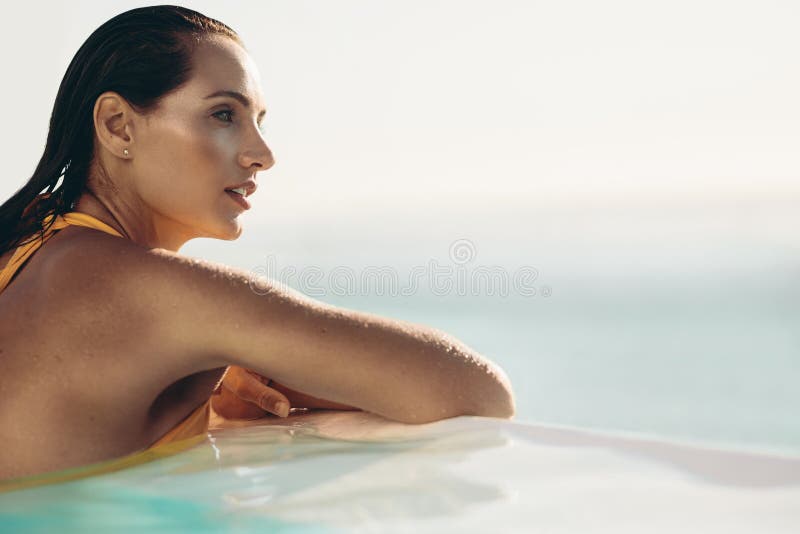 Femme attirante d?tendant dans la piscine d'infini photo libre de droits Femme attirante d?tendant dans la piscine d'infini photo libre de droits