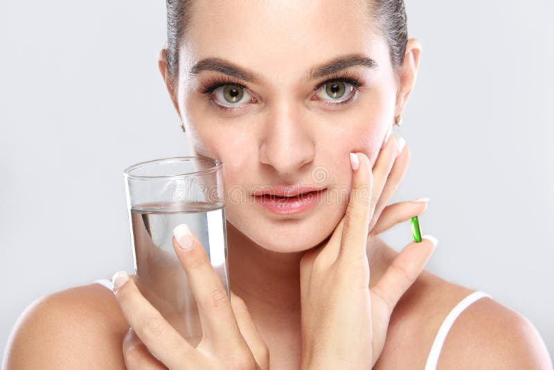 Femme attirante posant avec un verre de capsul de l'eau et de vitamine photos stock Femme attirante posant avec un verre de capsul de l'eau et de vitamine photos stock