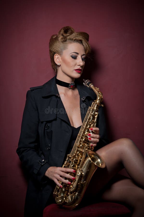 Femme attirante sexy avec le saxophone posant sur le fond rouge Jeune saxo jouant blond sensuel Instrument de musique, jazz images stock Femme attirante sexy avec le saxophone posant sur le fond rouge Jeune saxo jouant blond sensuel Instrument de musique, jazz images stock