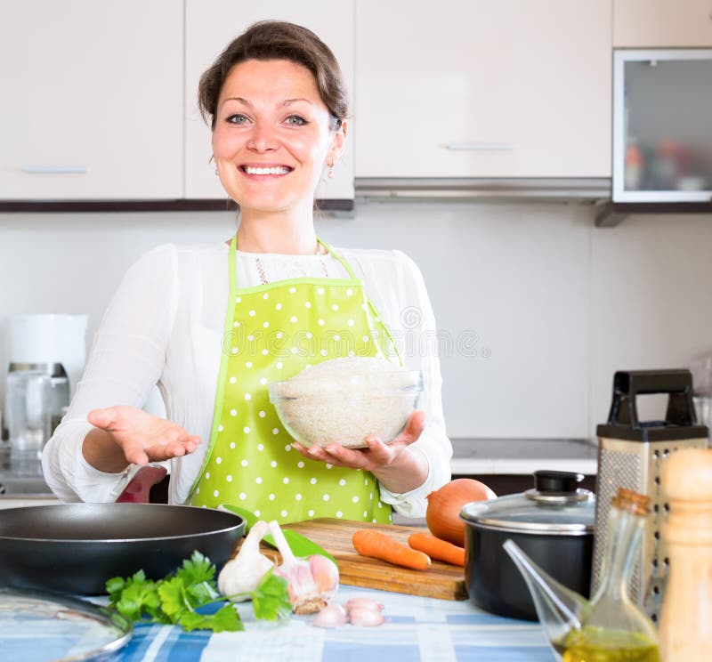 Femme au foyer faisant cuire la Paella dans la cuisine image stock Femme au foyer faisant cuire la Paella dans la cuisine image stock