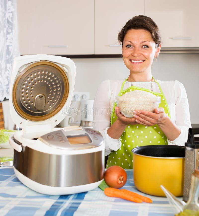 Femme au foyer faisant cuire le riz avec le multicooker images libres de droits Femme au foyer faisant cuire le riz avec le multicooker images libres de droits