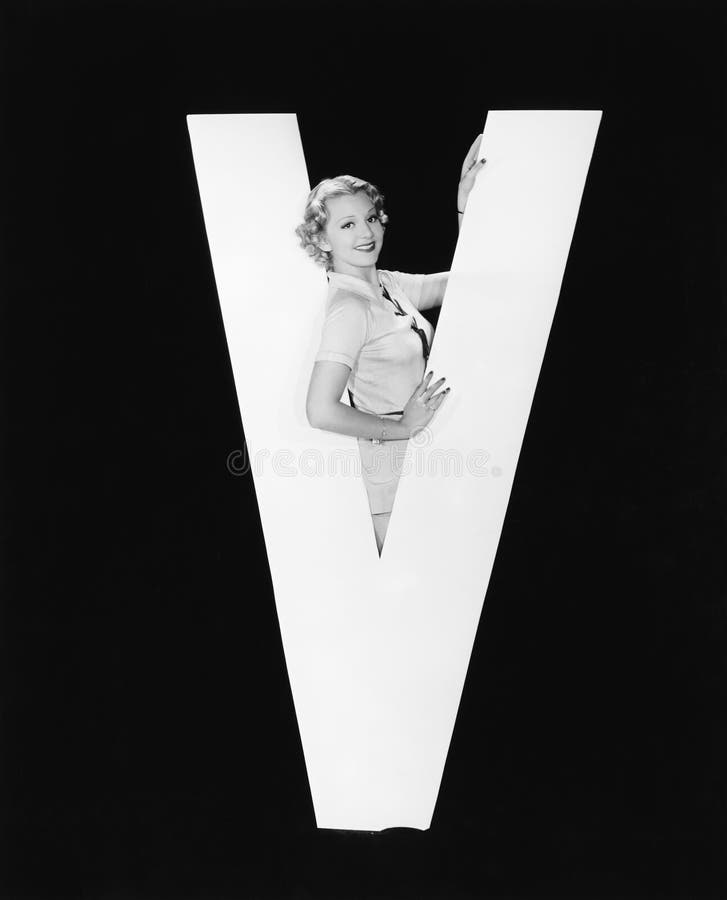 Femme au milieu de la lettre énorme V (toutes les personnes représentées ne sont pas plus long vivantes et aucun domaine n'existe images stock Femme au milieu de la lettre énorme V (toutes les personnes représentées ne sont pas plus long vivantes et aucun domaine n'existe images stock