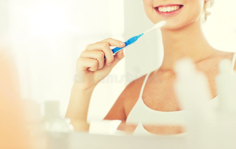 Femme avec des dents de nettoyage de brosse à dents à la salle de bains images libres de droits Femme avec des dents de nettoyage de brosse à dents à la salle de bains images libres de droits