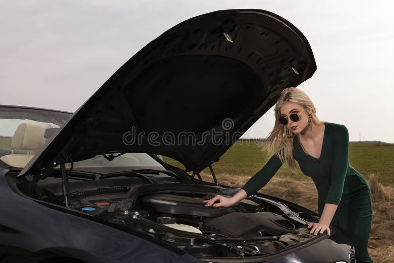 Femme avec des talons réparant sa voiture cassée image stock Femme avec des talons réparant sa voiture cassée image stock