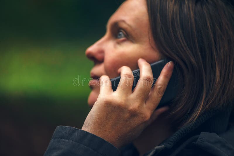 Femme avec l'expression sérieuse de visage parlant au téléphone en parc photo libre de droits