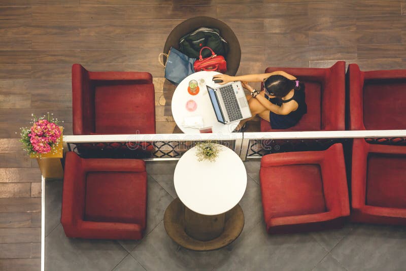 Femme avec l'ordinateur portable se reposant sur les tables d'une barre, vue courbe photo stock Femme avec l'ordinateur portable se reposant sur les tables d'une barre, vue courbe photo stock
