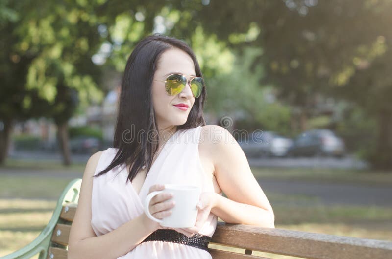Femme avec la tasse de café en parc image libre de droits Femme avec la tasse de café en parc image libre de droits