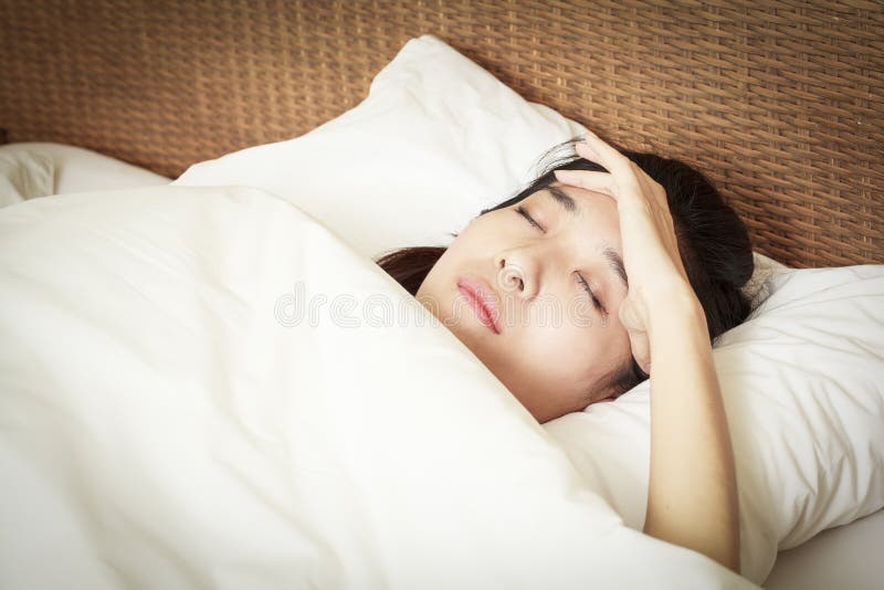 Femme avec le mal de tête se trouvant sur le lit image libre de droits Femme avec le mal de tête se trouvant sur le lit image libre de droits