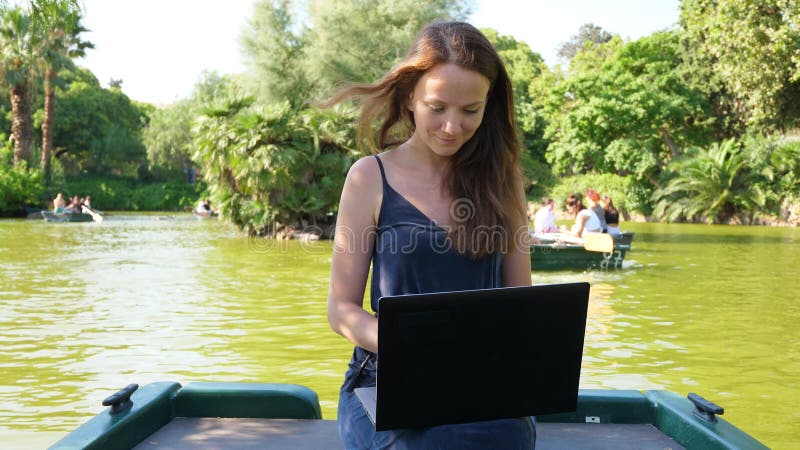 Femme avec le travail d'ordinateur portable à distance au parc d'été