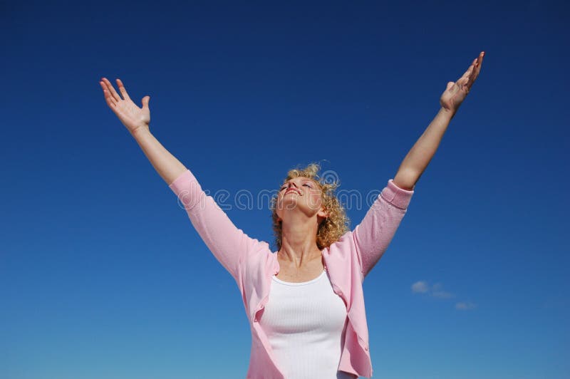 Woman with her arms wide open against a blue sky. Woman with her arms wide open against a blue sky