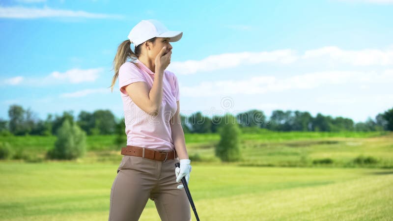 Woman with golf club closing mouth by hand, shocked with failed shot, loser, stock photo. Woman with golf club closing mouth by hand, shocked with failed shot, loser, stock photo