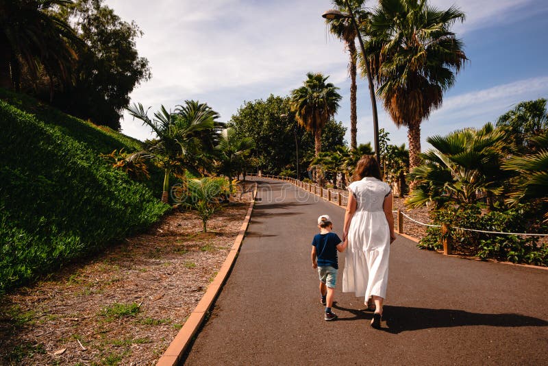 Femme avec un enfant en marchant le long d'une allée de palmiers photo libre de droits