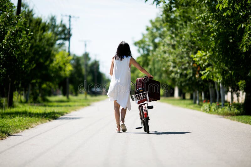 Femme avec un vélo de vintage dans une campagne image libre de droits Femme avec un vélo de vintage dans une campagne image libre de droits