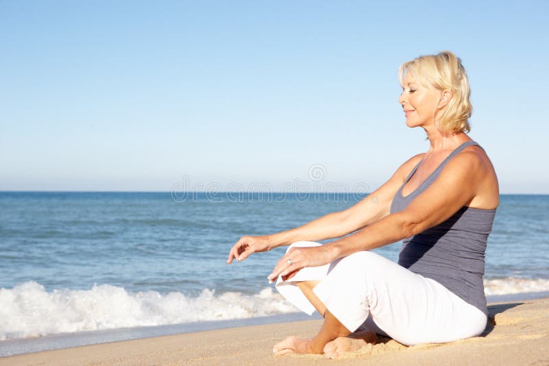 Femme aîné méditant sur la plage photos libres de droits Femme aîné méditant sur la plage photos libres de droits