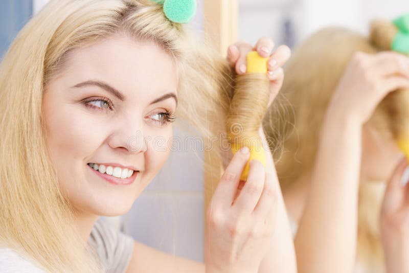 Femme blonde ? l'aide des rouleaux de cheveux photographie stock Femme blonde ? l'aide des rouleaux de cheveux photographie stock