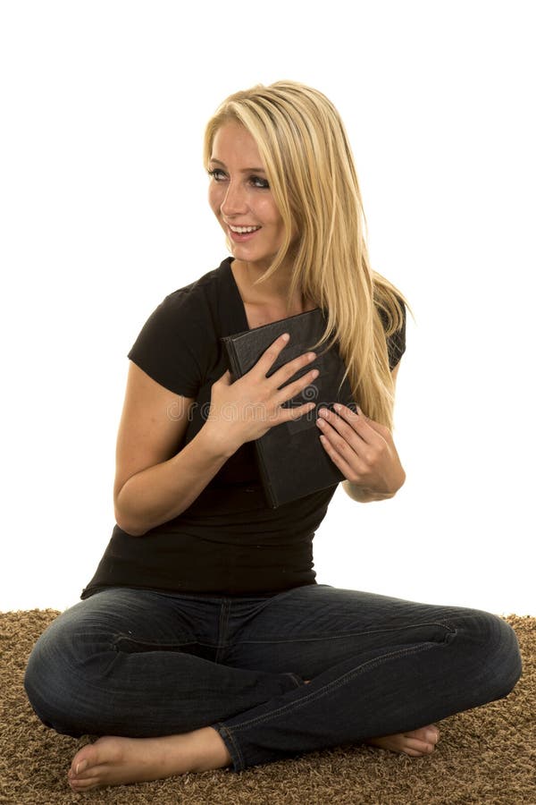 Femme blonde s'asseyant du côté de regard de livre de prise de tapis photographie stock Femme blonde s'asseyant du côté de regard de livre de prise de tapis photographie stock