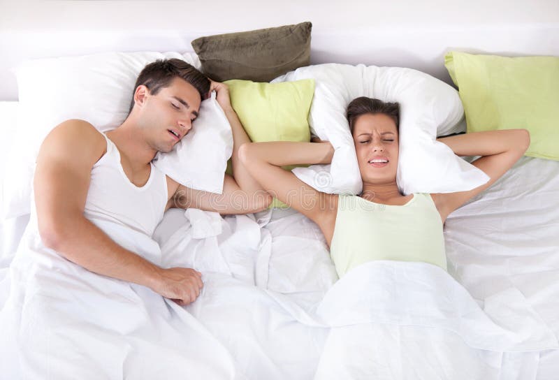 Femme bouleversée dans le lit avec son ami ronflant images stock Femme bouleversée dans le lit avec son ami ronflant images stock