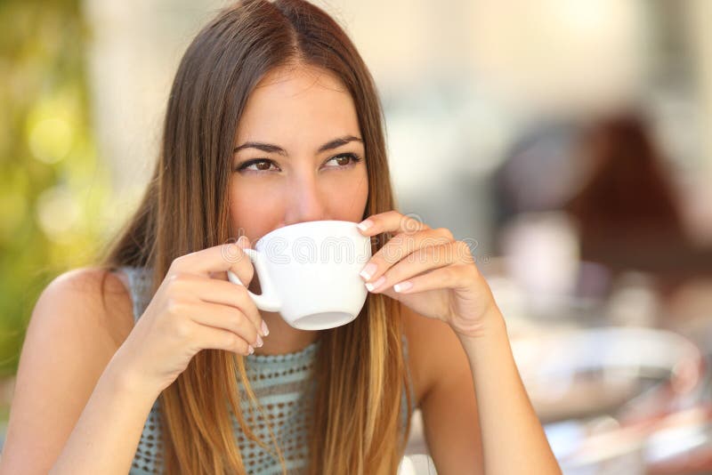 Femme buvant d'un café d'une tasse dans une terrasse de restaurant photographie stock Femme buvant d'un café d'une tasse dans une terrasse de restaurant photographie stock