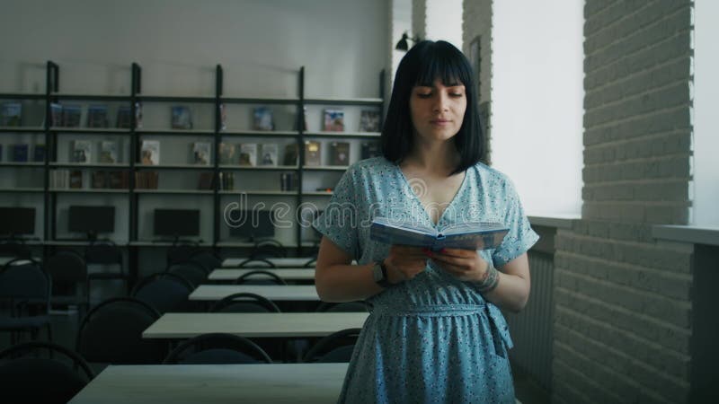 Femme captivée lecture livre debout dans une bibliothèque. portrait informatif avec profondeur de champ. apprentissage continu et banque de vidéos