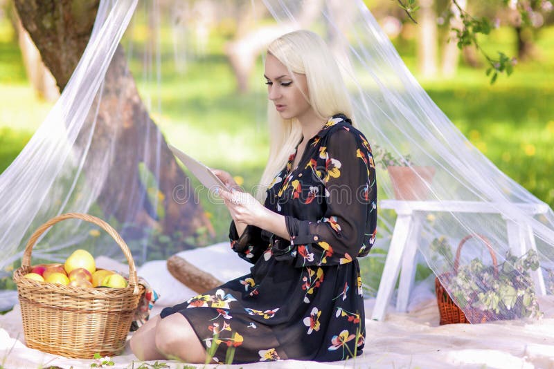 Femme caucasienne blonde employant le lecteur Outside de Tablette d'Ebook dans les avants images libres de droits Femme caucasienne blonde employant le lecteur Outside de Tablette d'Ebook dans les avants images libres de droits