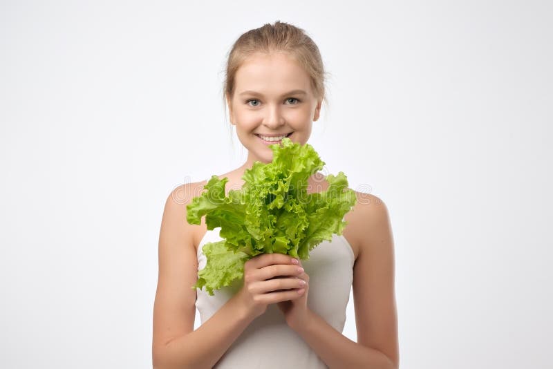 Femme caucasienne de sourire montrant la laitue d'isolement au-dessus du fond blanc photos libres de droits Femme caucasienne de sourire montrant la laitue d'isolement au-dessus du fond blanc photos libres de droits