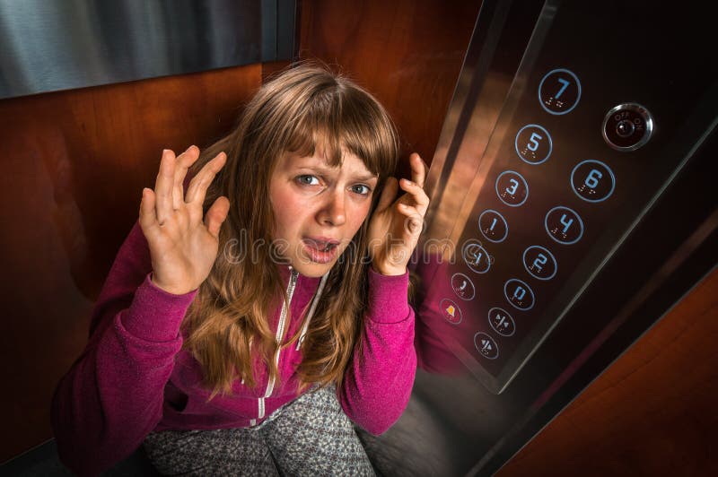 Femme choquée avec la claustrophobie dans l'ascenseur mobile image libre de droits Femme choquée avec la claustrophobie dans l'ascenseur mobile image libre de droits