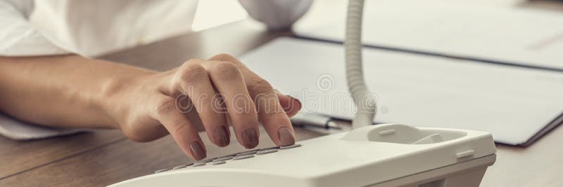 Femme composant un numéro de téléphone au téléphone blanc de ligne terrestre photos libres de droits Femme composant un numéro de téléphone au téléphone blanc de ligne terrestre photos libres de droits