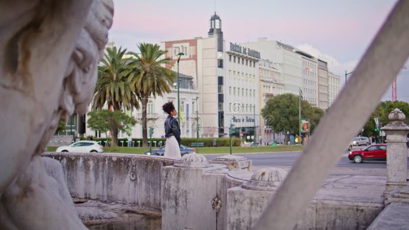 Femme contemplative debout fontaine en ville. femme africaine élégante banque de vidéos