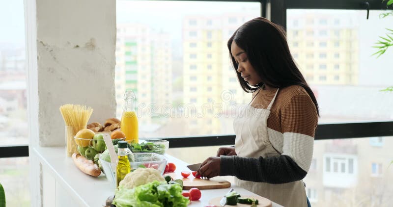 Femme coupant la tomate fraîche dans la cuisine