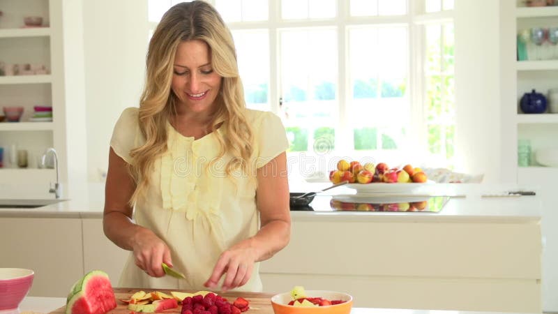 Femme coupant le fruit frais d'été dans la cuisine