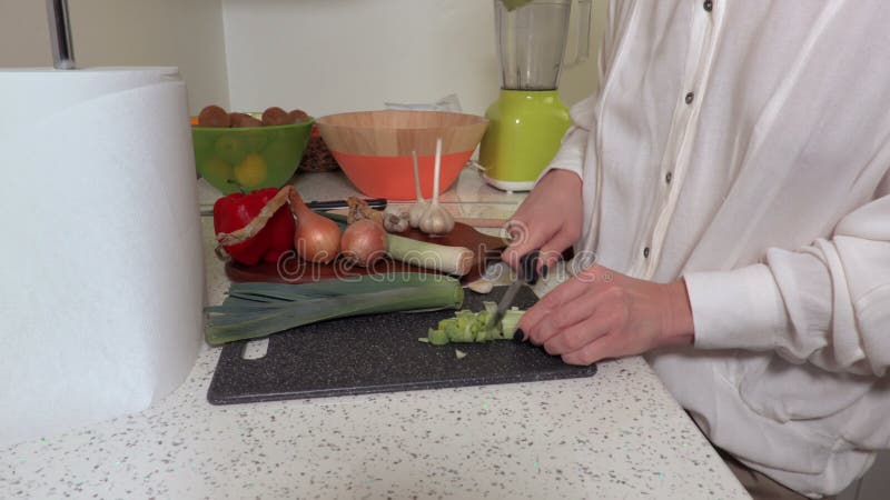 Femme coupant le poireau dans la cuisine