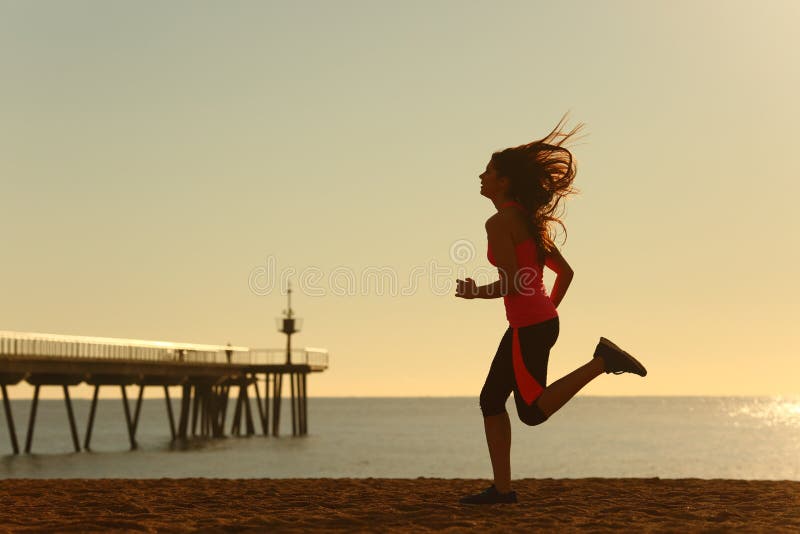 Femme courant sur la plage au lever de soleil image libre de droits Femme courant sur la plage au lever de soleil image libre de droits